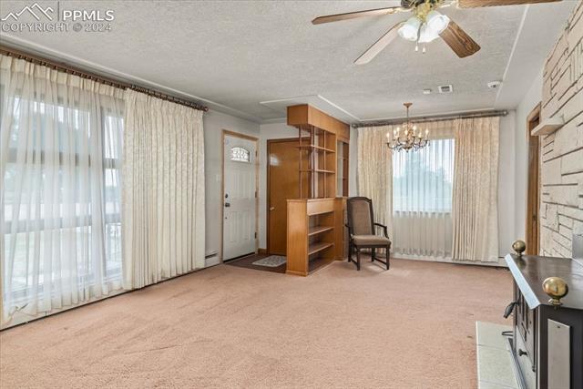28018 County Farm Road Pueblo, CO 81006 - Photo 3 of 50 Sitting room featuring ceiling fan with notable chandelier, baseboard heating, carpet, and a textured ceiling