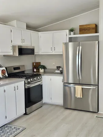 a kitchen with stainless steel appliances granite countertop a refrigerator a stove a sink and white cabinets