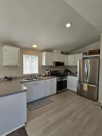 a kitchen with granite countertop white cabinets and stainless steel appliances