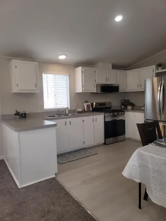 a kitchen with stainless steel appliances granite countertop a stove a sink a refrigerator a microwave and white cabinets