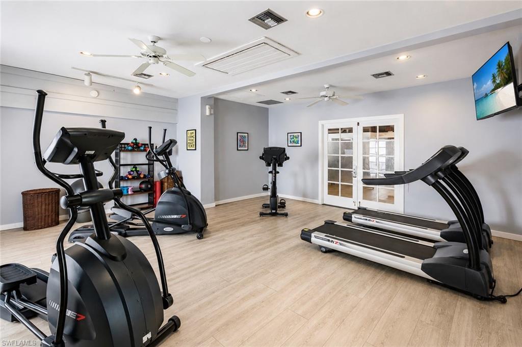 600 Neapolitan Way, Unit 449 Naples, FL 34103 - Photo 24 of 44 Fitness room with wood-finish flooring, two ceiling fans, recessed lighting, and double French doors with frosted glass panels