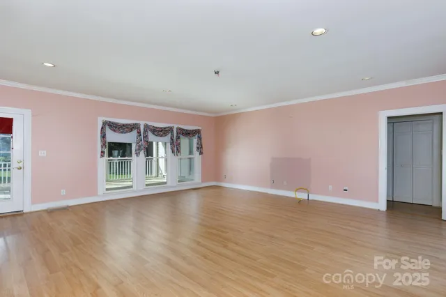 a view of an empty room with wooden floor and windows
