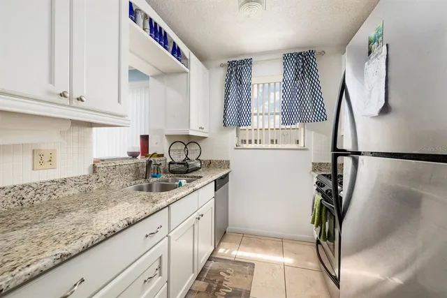 a kitchen with stainless steel appliances granite countertop a sink a refrigerator and a granite counter tops