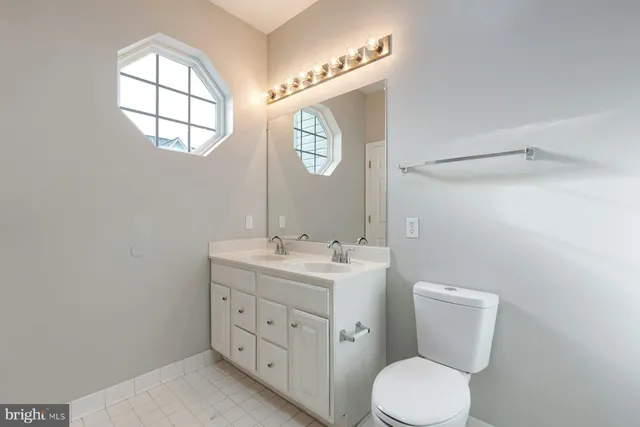 a bathroom with a toilet sink vanity and mirror