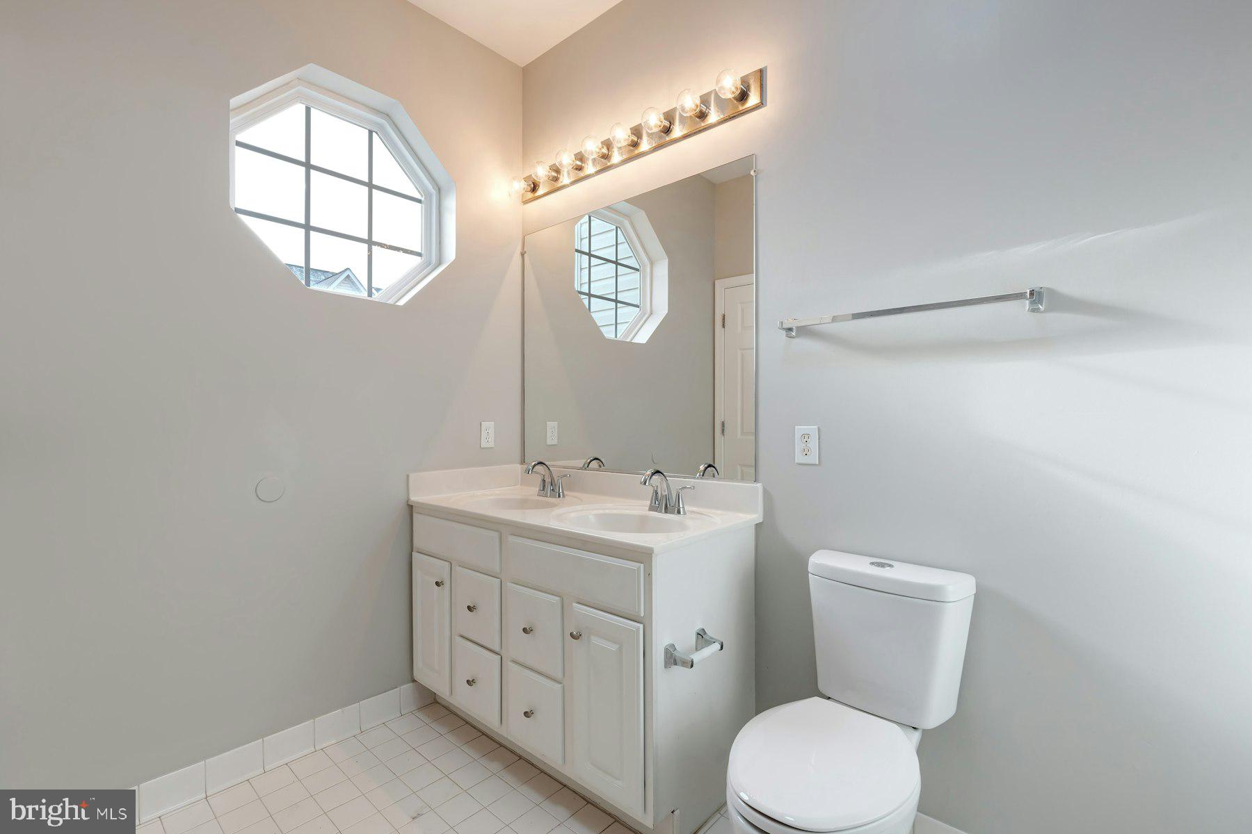 1838 Cedar Cove Way, Unit 201 Woodbridge, VA 22191 - Photo 18 of 38 a bathroom with a toilet sink vanity and mirror