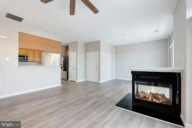 a view of an empty room with wooden floor and a fireplace