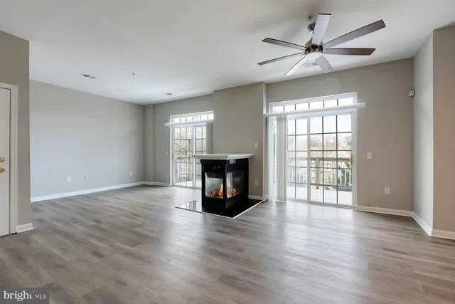 an empty room with wooden floor fireplace and windows