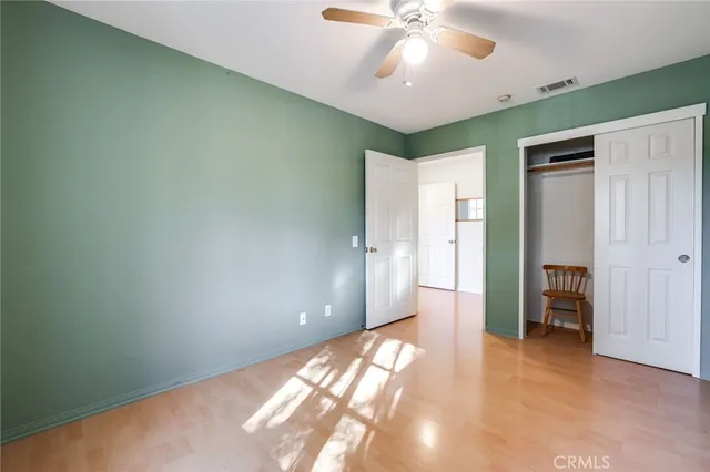 an empty room with closet and a chandelier fan