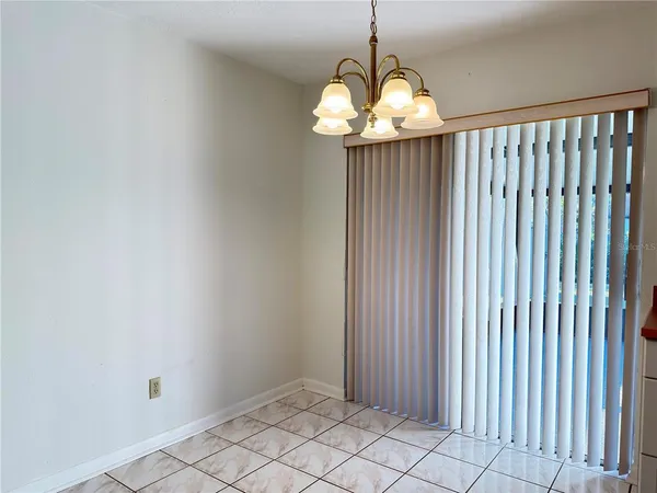 a view of an empty room with wooden floor and a chandelier