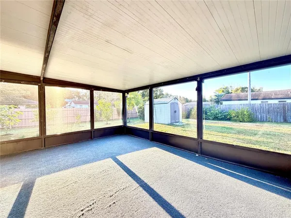 a view of an empty room with wooden floor and a large window