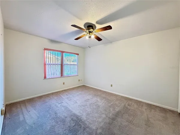 an empty room with windows and fan