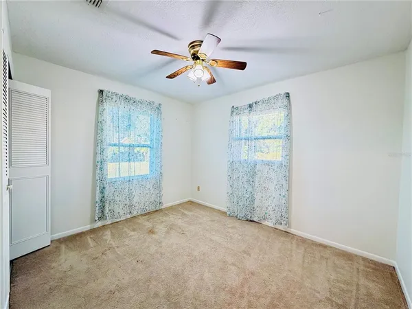 an empty room with fan and windows