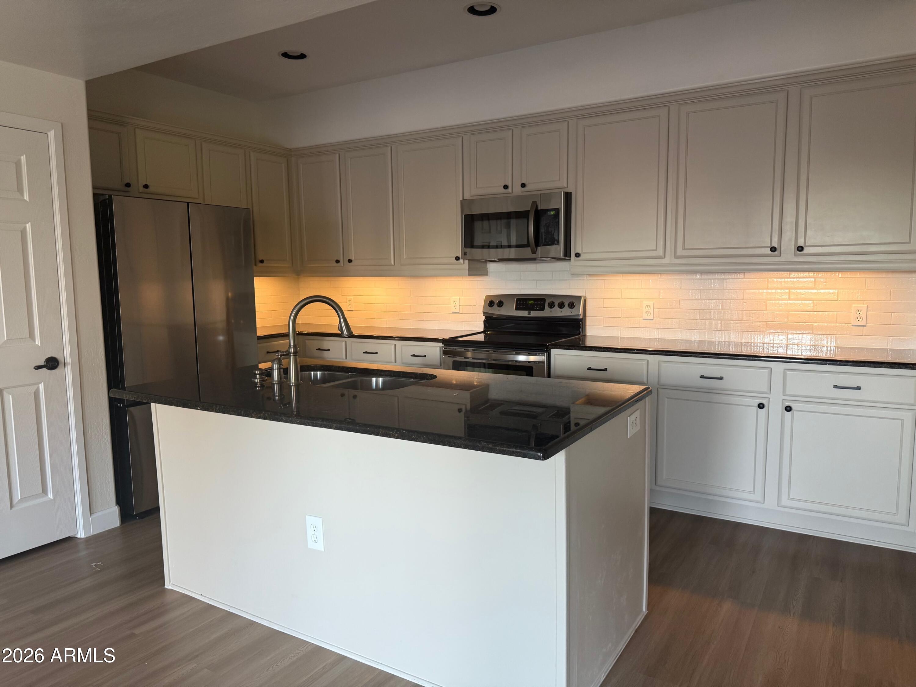 3935 East Rough Rider Road, Unit 1057 Phoenix, AZ 85050 - Photo 8 of 21 a kitchen with stainless steel appliances a sink a stove a microwave and cabinetry