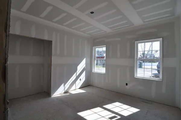 an empty room with wooden floor ceiling fan and windows
