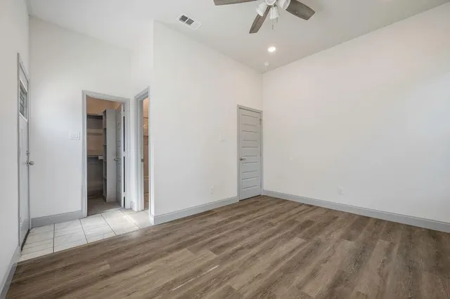 an empty room with wooden floor chandelier fan and windows