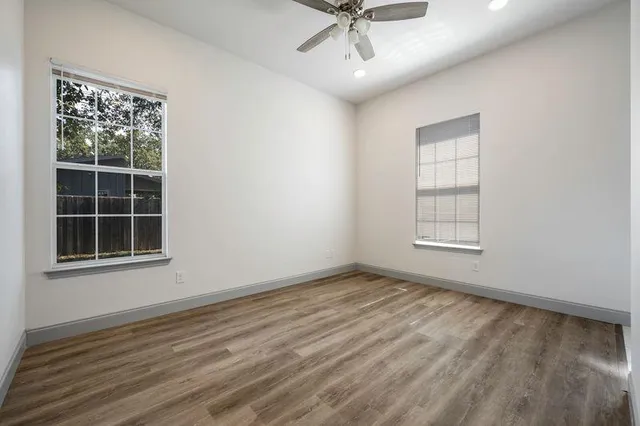 an empty room with wooden floor cabinet and windows