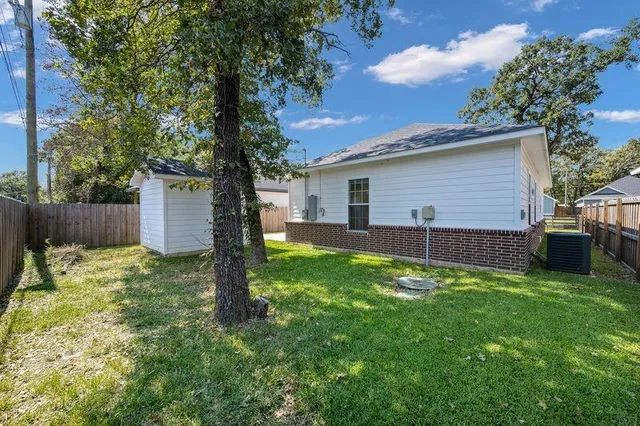 a backyard of a house with plants and a tree