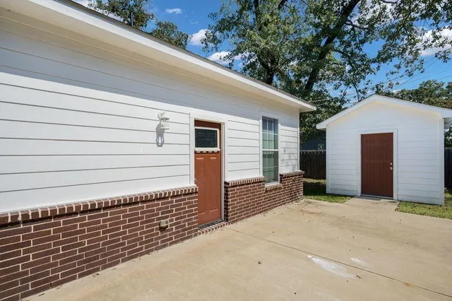 a view of a house with a small yard and large tree