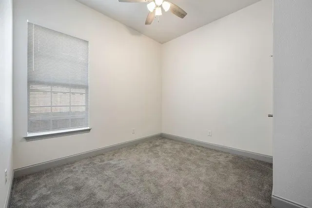 an empty room with a chandelier fan and windows