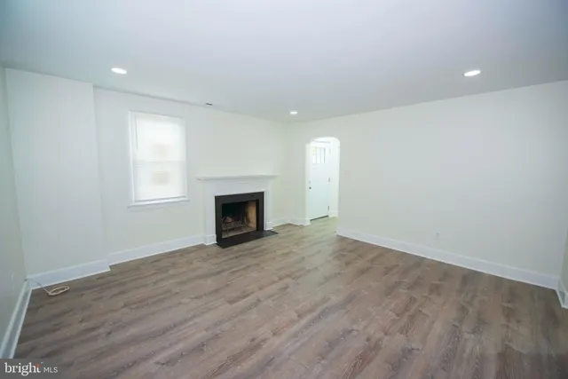 an empty room with wooden floor and fireplace
