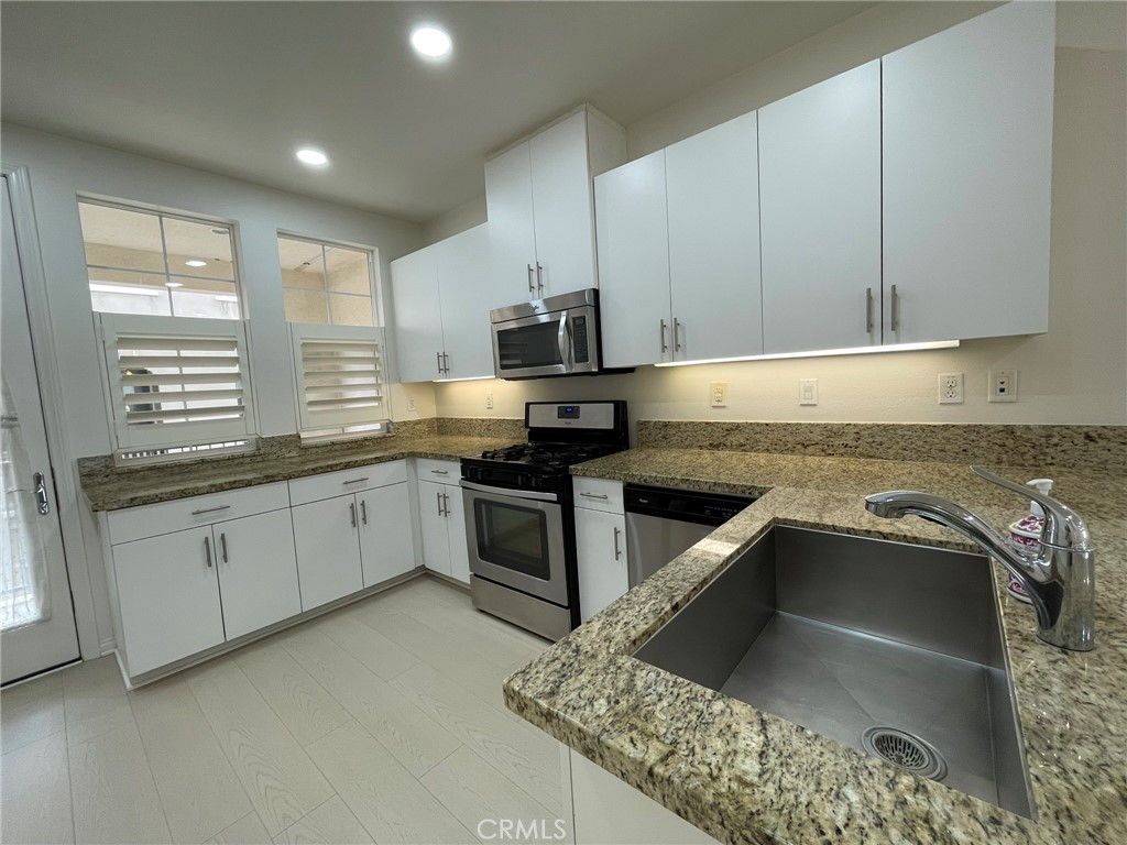 810 The Promenade, Unit C Azusa, CA 91702 - Photo 14 of 38 a kitchen with granite countertop a sink stainless steel appliances and cabinets