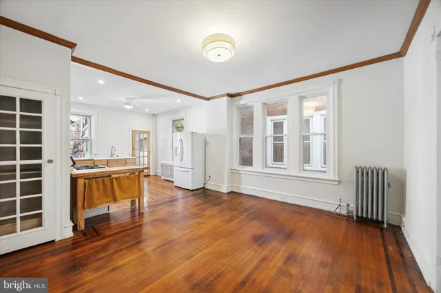 a view of an empty room with a window and wooden floor