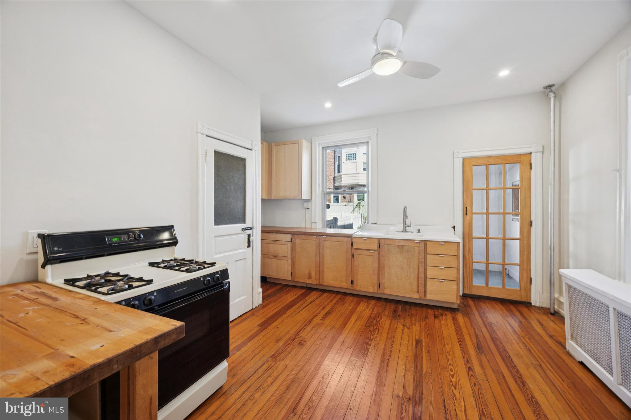 1227 South 53rd Street Philadelphia, PA 19143 - Photo 15 of 31 a kitchen with a stove a sink wooden floor and a window