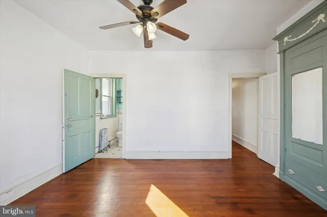 an empty room with wooden floor cabinet and windows