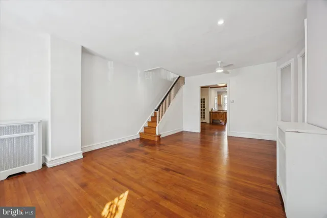 a view of an empty room with wooden floor and stairs