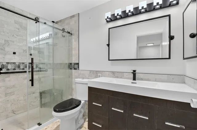 a bathroom with a sink vanity mirror and toilet