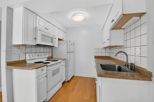 a kitchen with granite countertop a sink a stove and cabinets