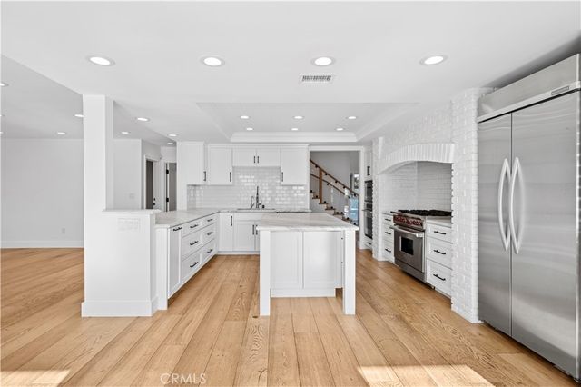 a large kitchen with stainless steel appliances kitchen island a large counter top and a refrigerator