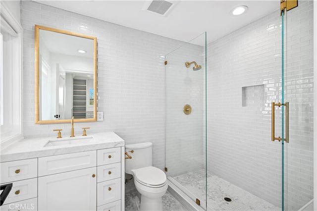 a bathroom with a shower sink vanity mirror and toilet