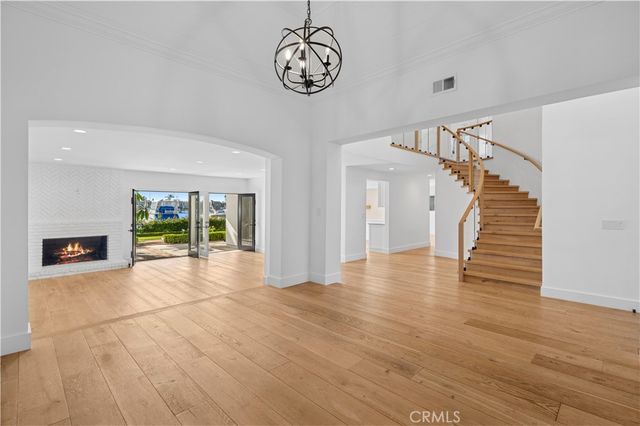 a view of an empty room with wooden floor fireplace and a window