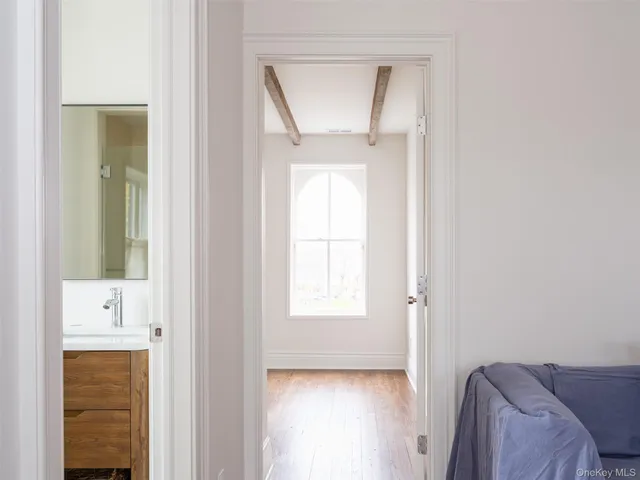 a view of hallway with window and wooden floor