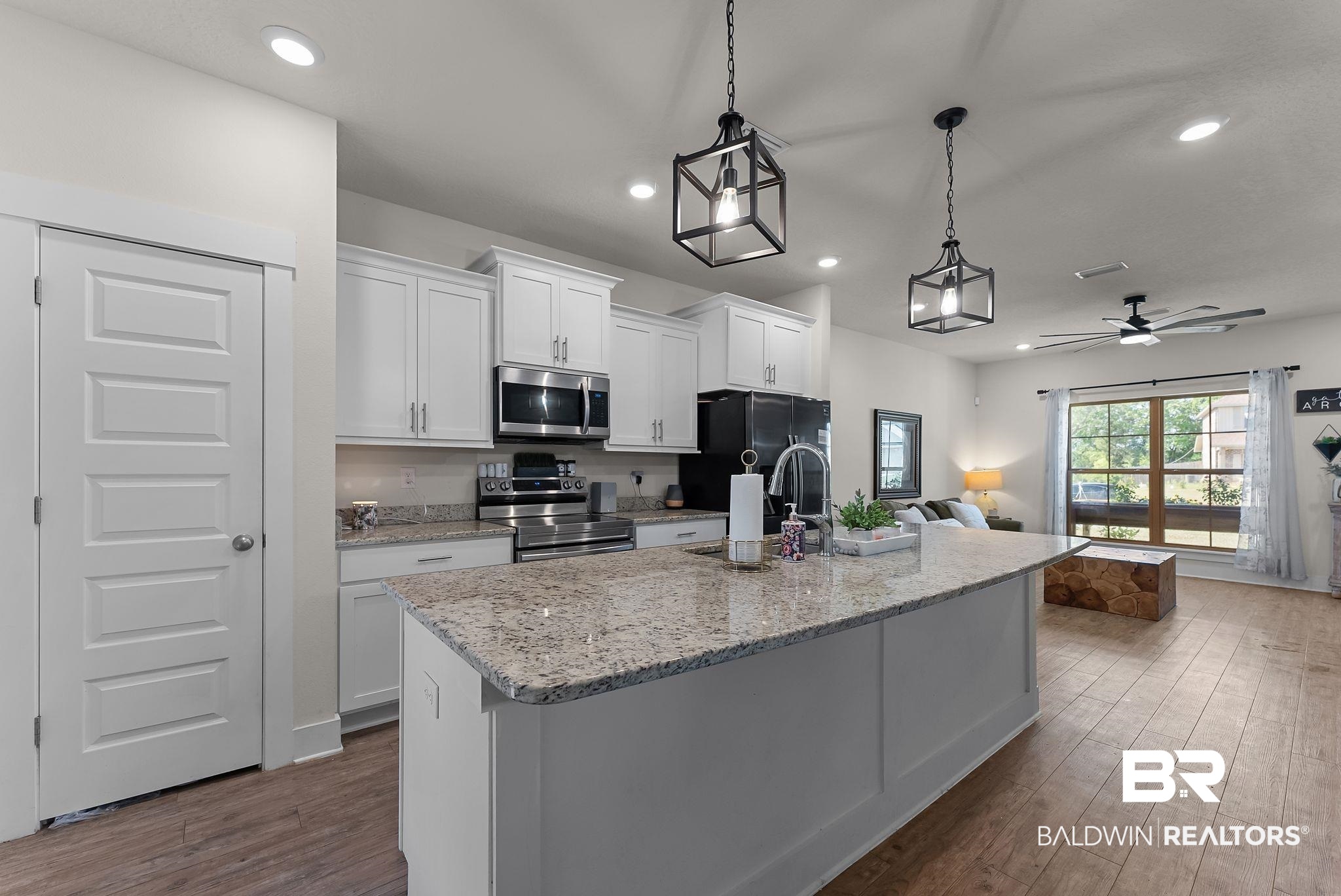 16607 Prado Loop Loxley, AL 36551 - Photo 14 of 46 Open-concept kitchen featuring an expansive island with a light-toned countertop, white cabinetry, recessed lighting, and stainless steel appliances