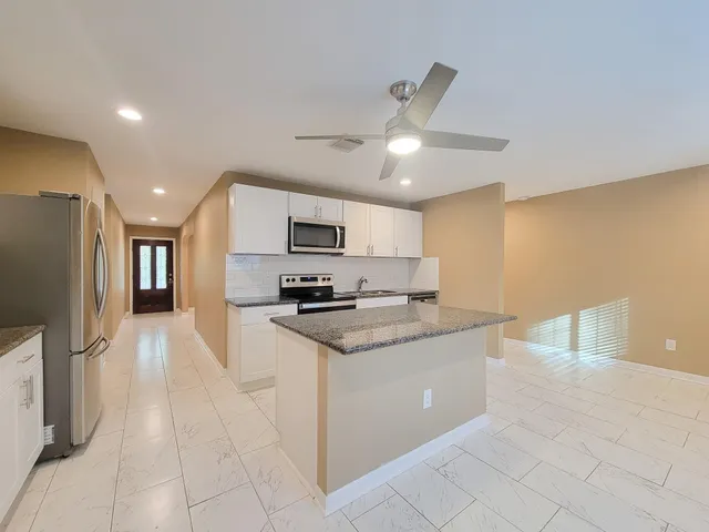 a kitchen with stainless steel appliances granite countertop a refrigerator a stove top oven a sink and dishwasher