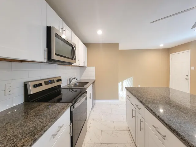 a kitchen with stainless steel appliances granite countertop a sink and a microwave