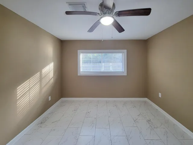 an empty room with windows and fan