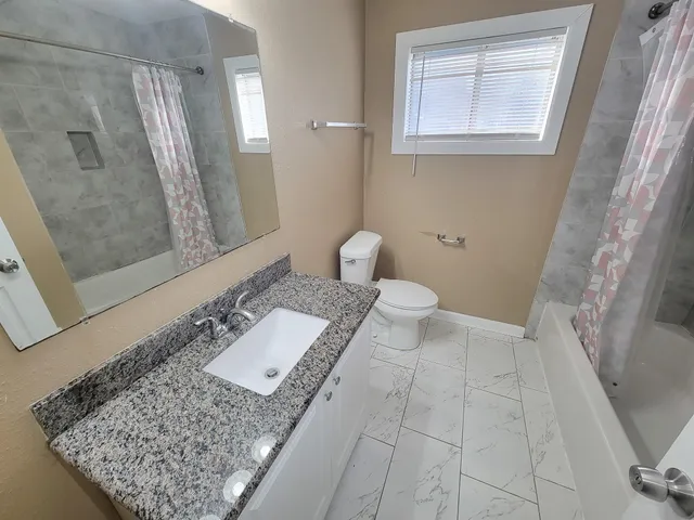 a bathroom with a granite countertop sink and a mirror