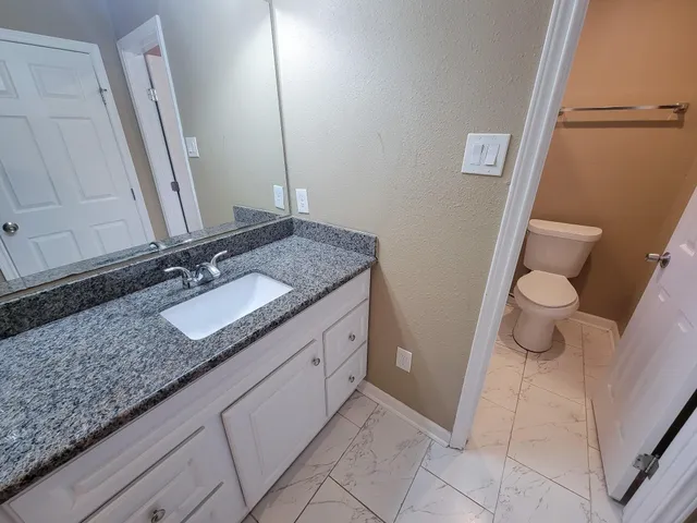 a bathroom with a granite countertop sink and a mirror