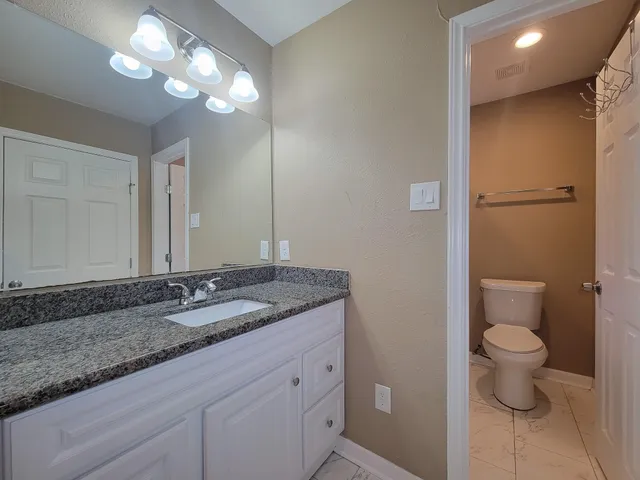 a bathroom with a granite countertop sink a toilet and a mirror