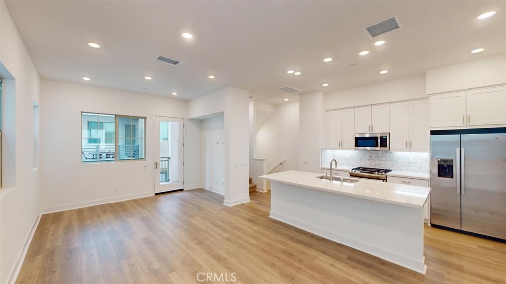 1689 Intrepid Lane San Pedro, CA 90732 - Photo 14 of 51 a large white kitchen with wooden floor and stainless steel appliances