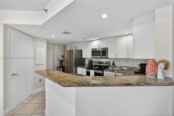 a kitchen with granite countertop a sink a stove a counter top space and cabinets