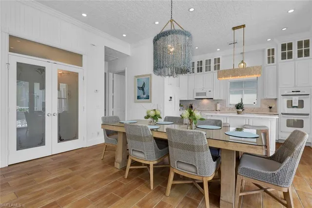 a dining room with stainless steel appliances kitchen island granite countertop a table chairs and a refrigerator