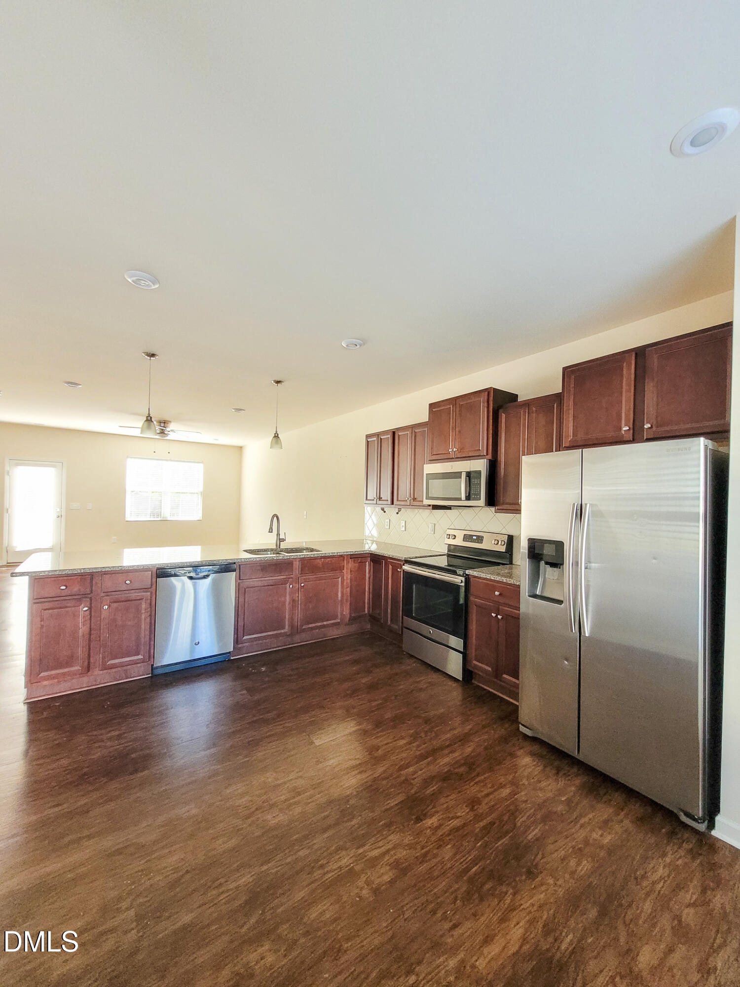8951 Commons Townes Drive Raleigh, NC 27616 - Photo 7 of 40 a kitchen with stainless steel appliances kitchen island granite countertop a refrigerator a sink a stove and oven with wooden floors