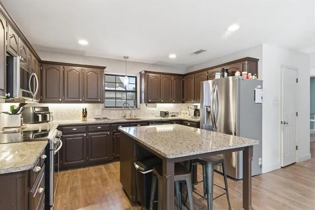 a kitchen with granite countertop a center island and stainless steel appliances