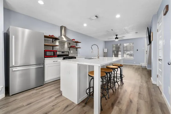 a kitchen with stainless steel appliances a refrigerator a stove a sink dishwasher and a dining table with wooden floor