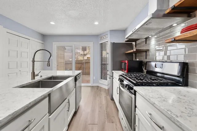 a kitchen with stainless steel appliances granite countertop a sink stove and cabinets
