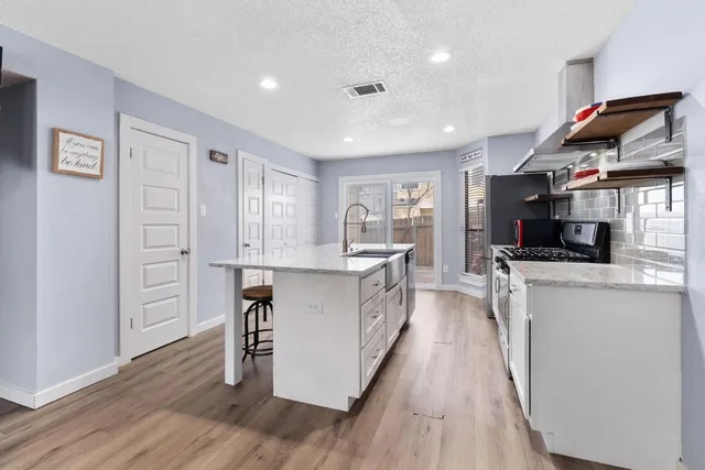a kitchen with granite countertop a refrigerator stove and wooden floor